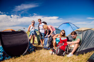 Teenagers in front of tents packing, summer music festival